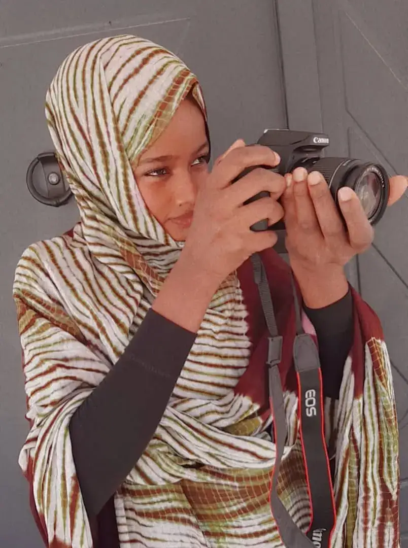 خديجة ترفع الكاميرا إلى عينها وهي تلتقط صورة
