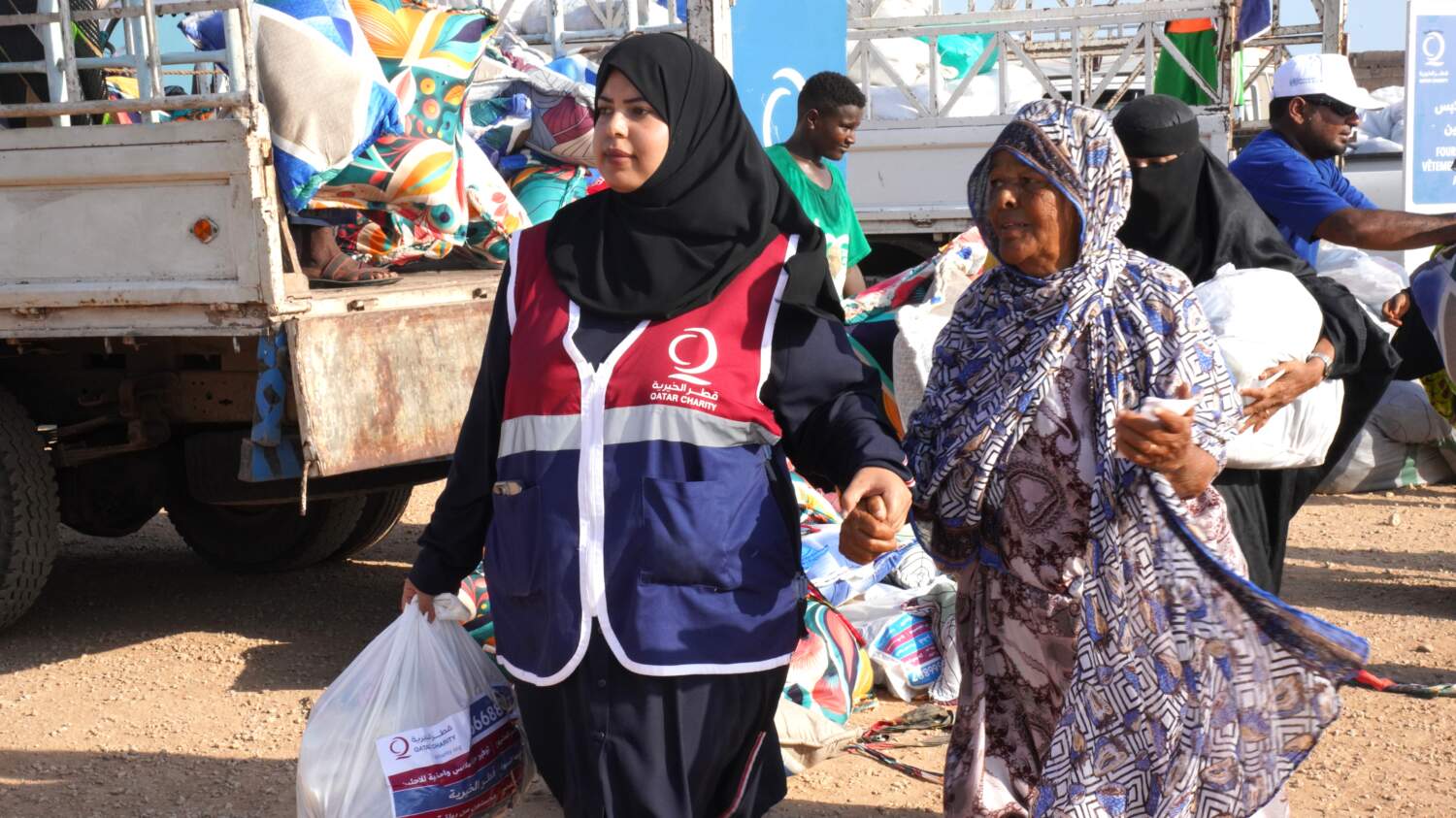 متطوعة من قطر الخيرية تمسك بيد لاجئة يمنية مسنة أثناء توزيع المساعدات في جيبوتي