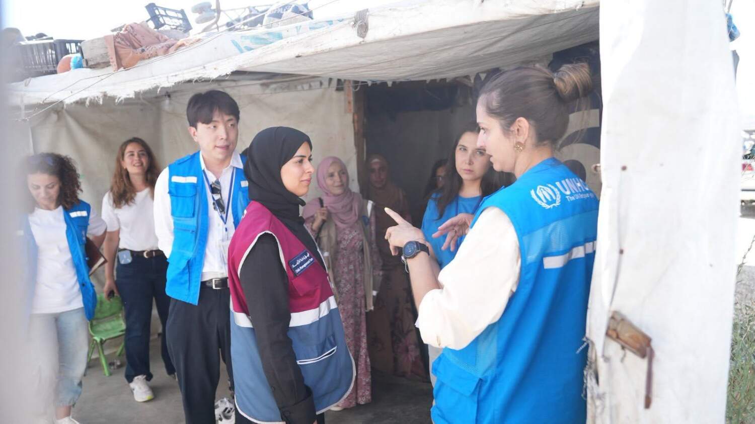 Qatar Charity and UNHCR staff speaking with families outside a shelter
